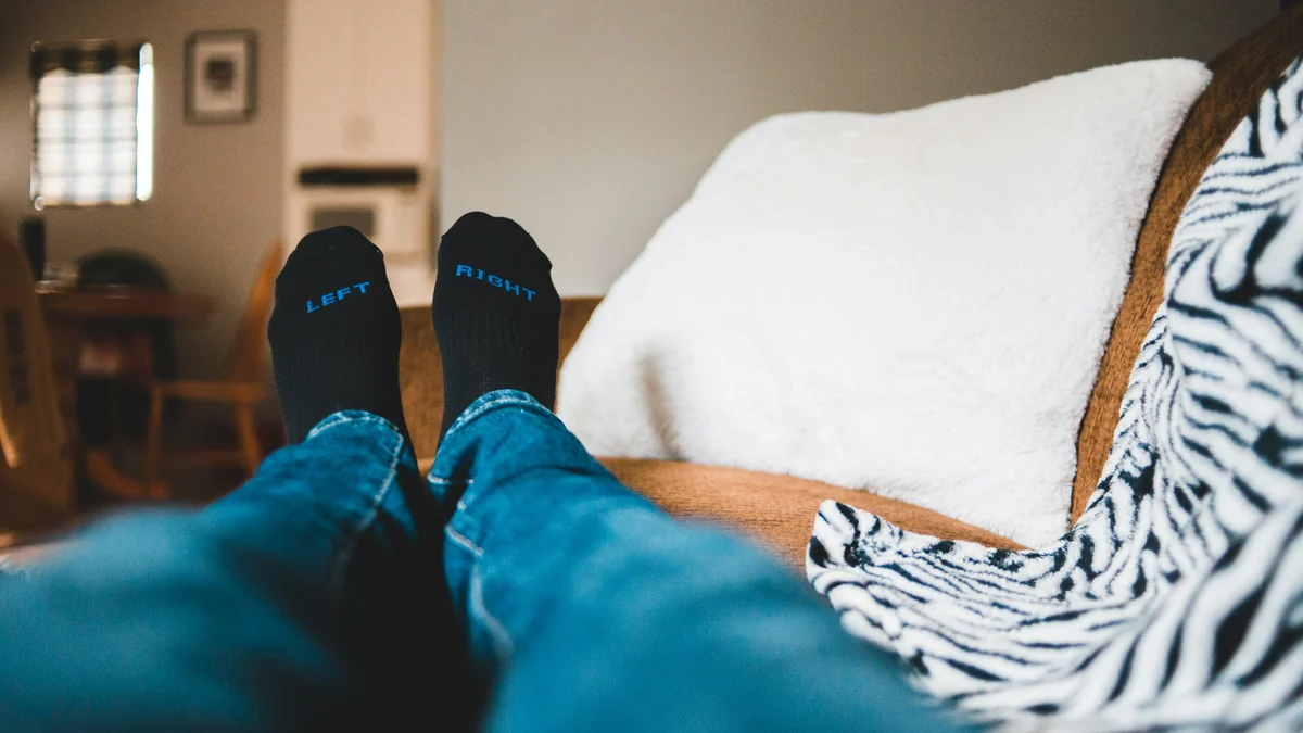 Feet in socks raised and resting on a sofa