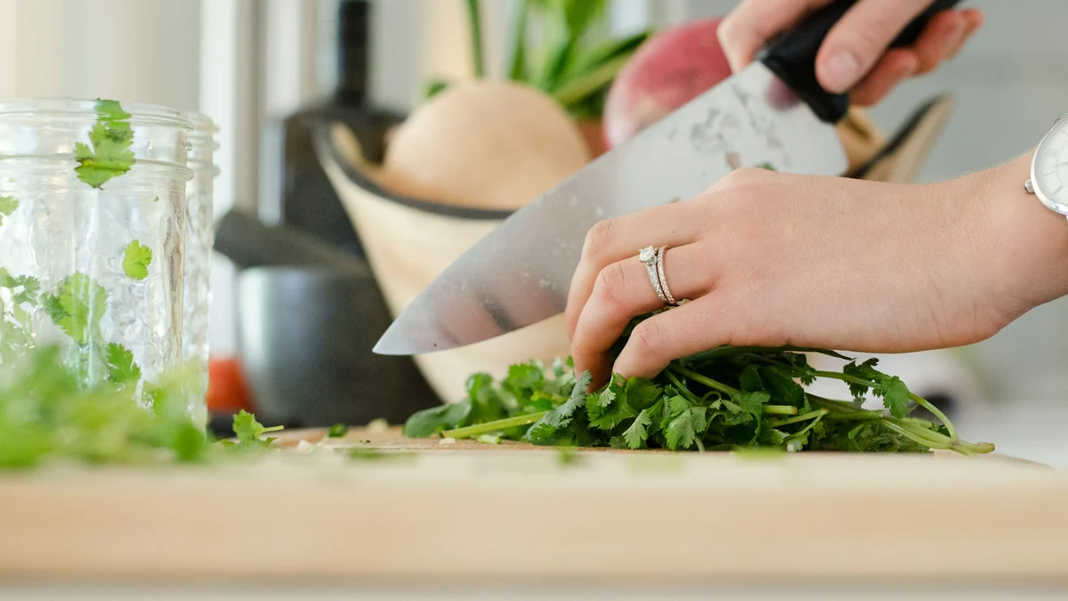 Hands chopping fresh greens on a cutting board